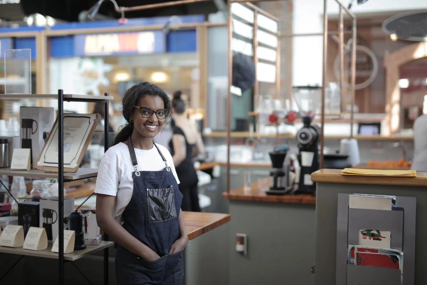 Barista con delantal de pie en su cafetería.