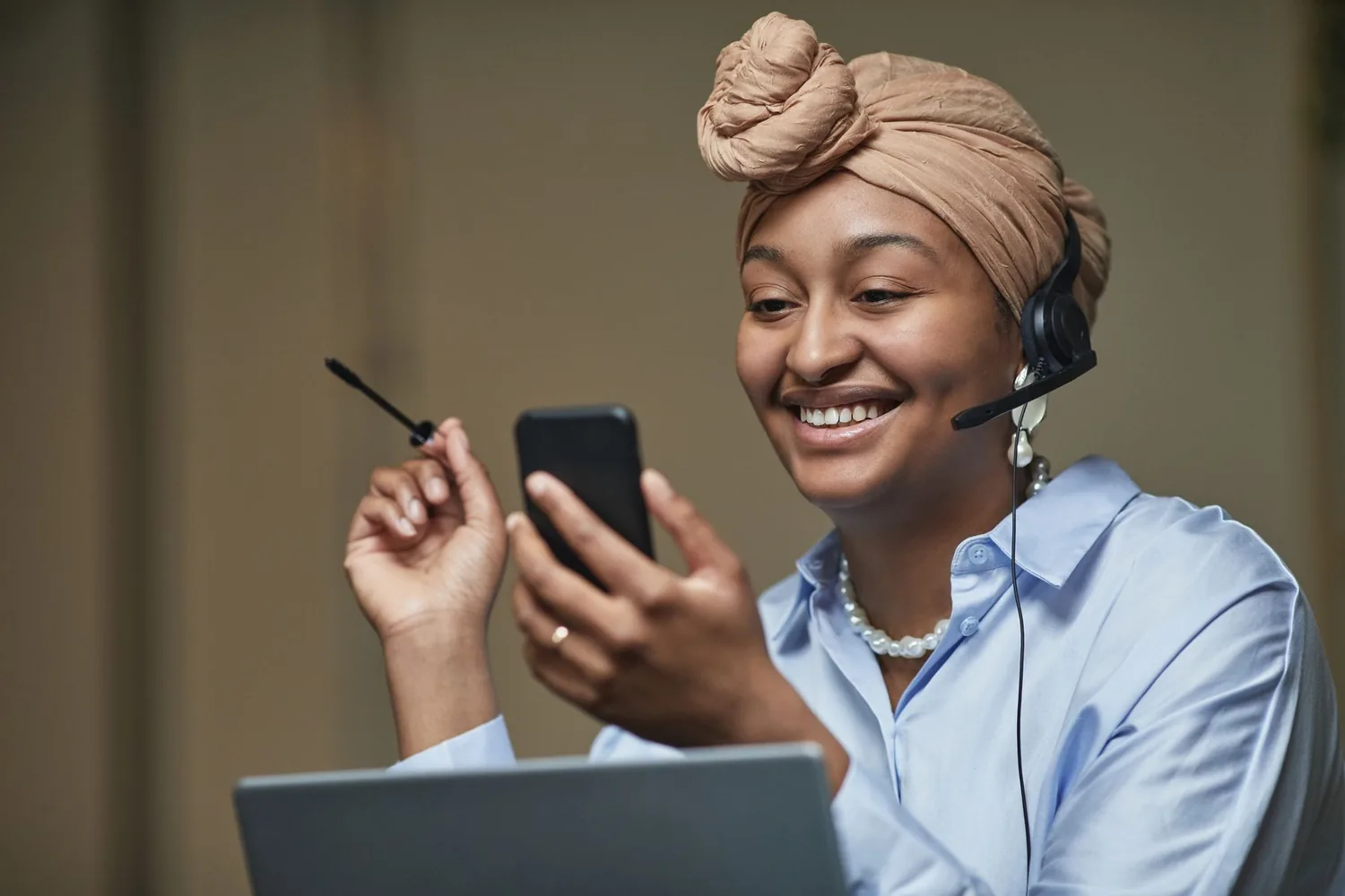 Asesora de Ketal Network sonriendo mientras atiende a una clienta por teléfono y computador.